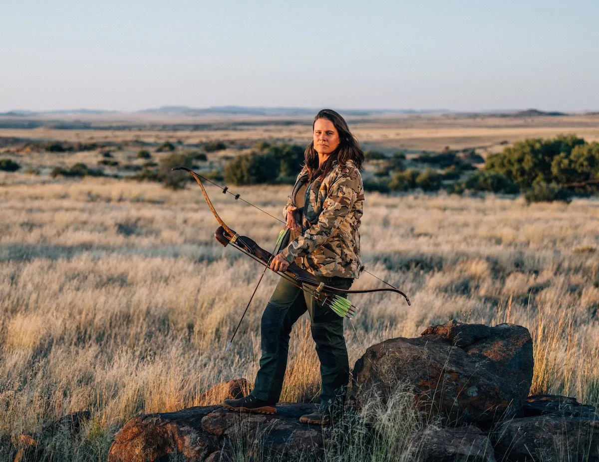 A woman dressed in camouflage and holding a bow and arrow in 'Alone' Season 12