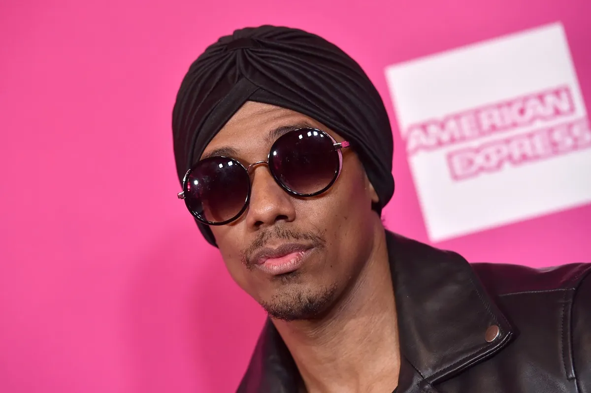 Nick Cannon posing at the Billboard Women in Music 2017 wearing a black outfit and sunglasses.