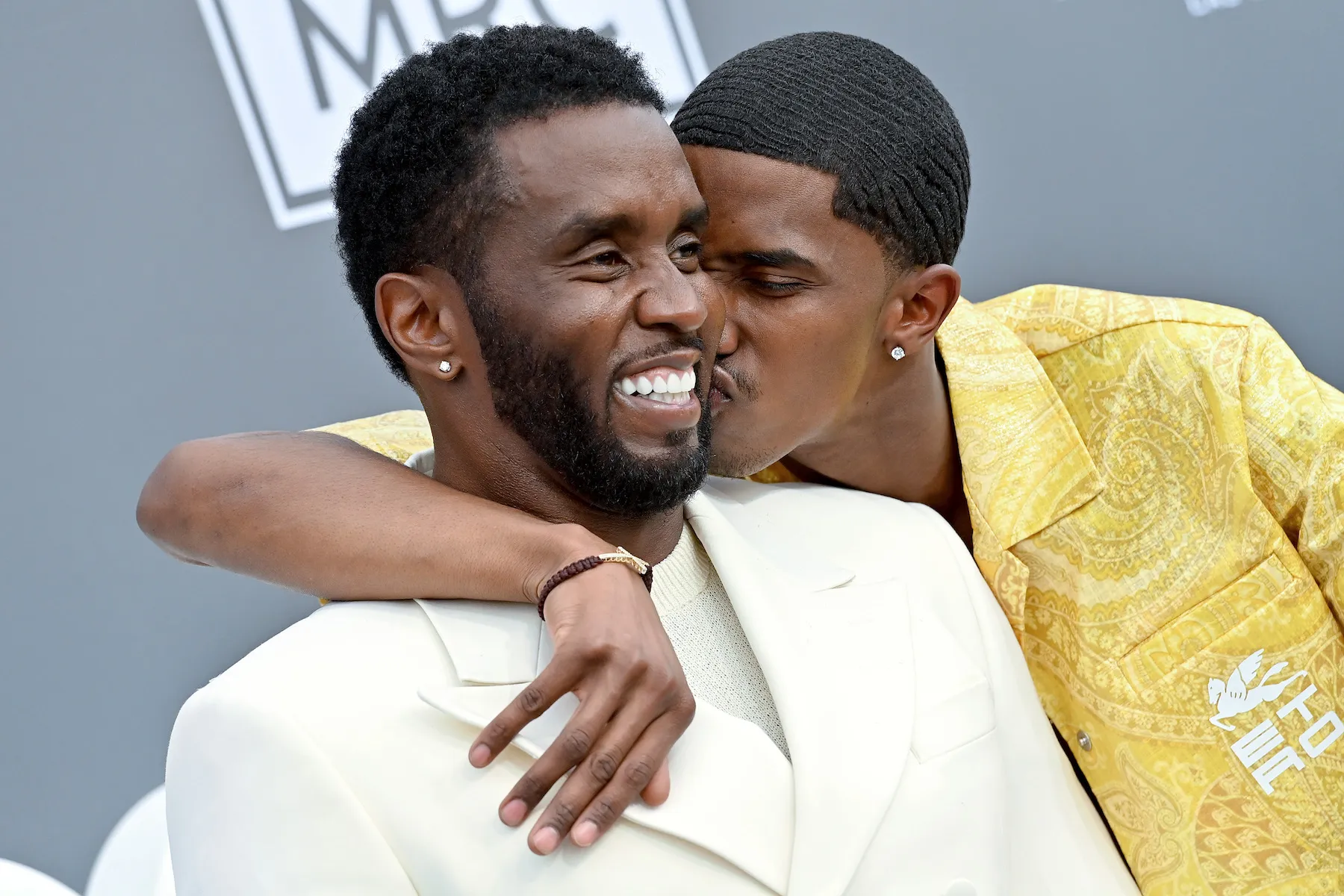 Sean 'Diddy' Combs and Christian 'King' Combs hugging at the 2022 Billboard Music Awards. Christian has his arm around Diddy's neck, and he kisses his cheek.